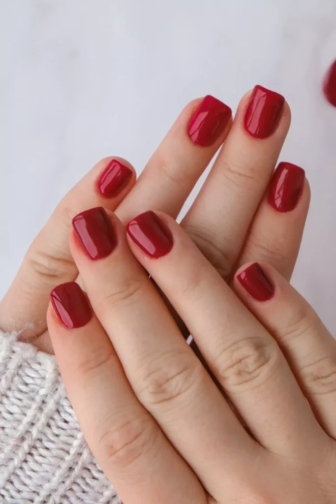 Natural short square nails painted in a solid, classic creamy cherry red polish.