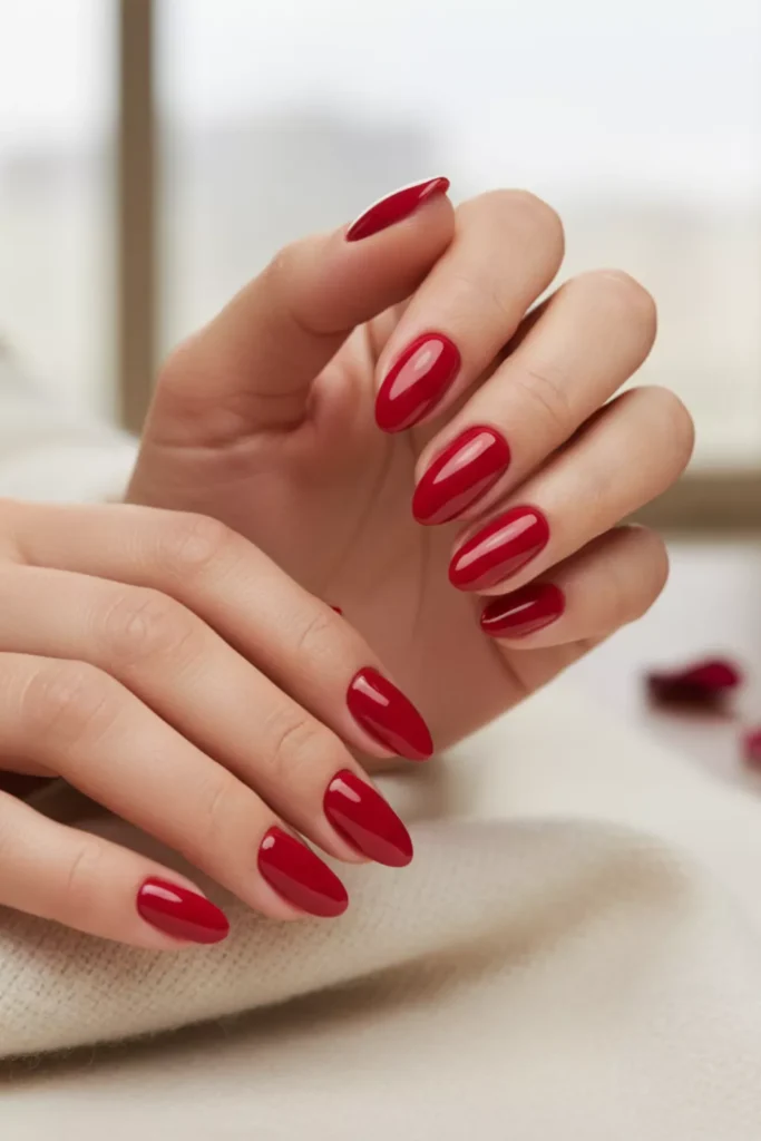 Elegant hands with medium-length oval nails painted in a classic, glossy deep red polish.