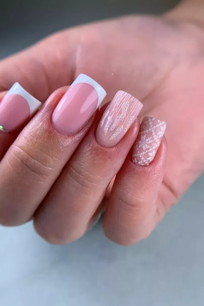 Glossy square nails featuring a pink base with thick white French tips, a white sweater-knit texture accent nail, and delicate snowflake patterns.