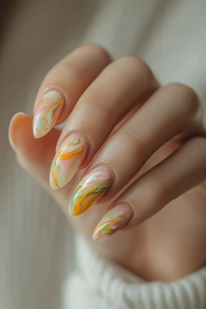 Long almond-shaped nails with a glossy white base featuring a vibrant multi-colored marble swirl design in orange, pink, green, and gold.