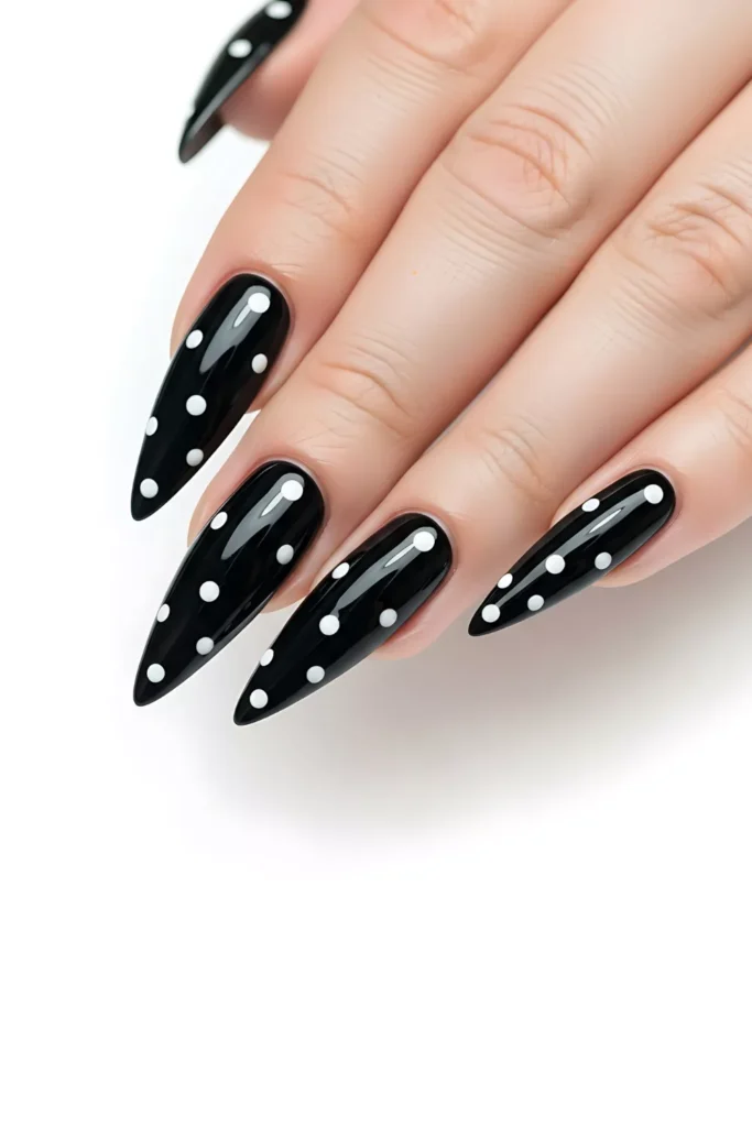 Long, high-gloss black stiletto nails decorated with a minimalist white polka dot pattern of varying sizes across each nail.