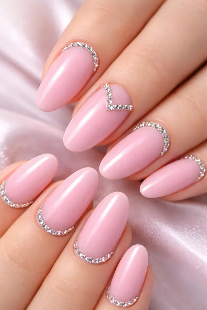 Pink nails with rhinestone accents along cuticle line, glam pink nail ideas.
