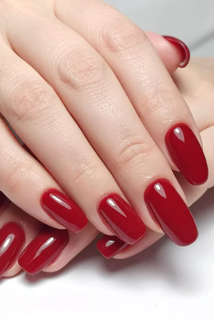 Medium almond-shaped nails in a sophisticated glossy dark crimson red.