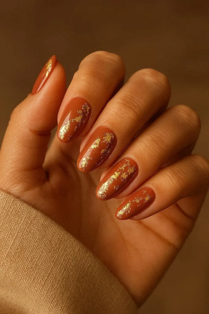Coffin nails with warm terracotta base and gold foil accent nail art for fall