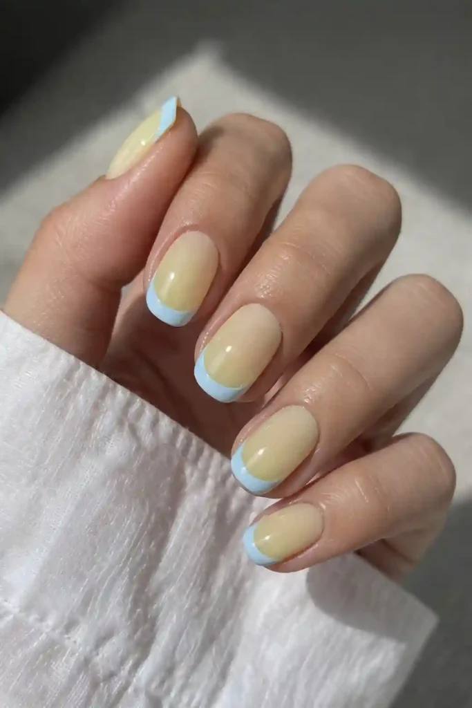 Soft baby blue French tips over a sheer lemon base: a fresh, modern take on the classic mani.