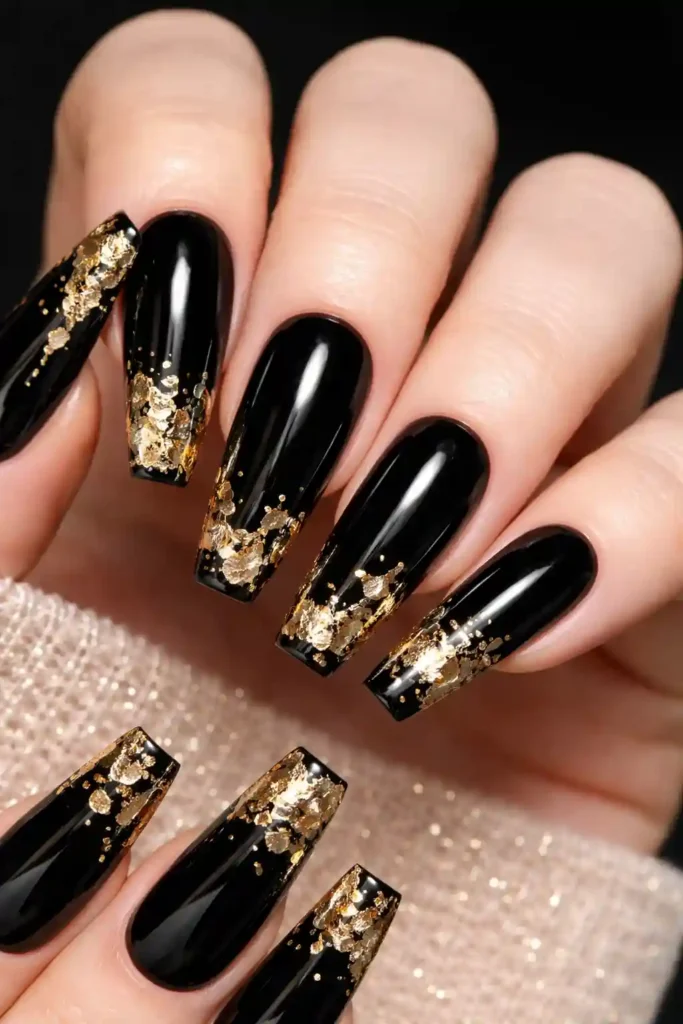 Glossy black coffin nails with irregular gold foil accents on each tip
