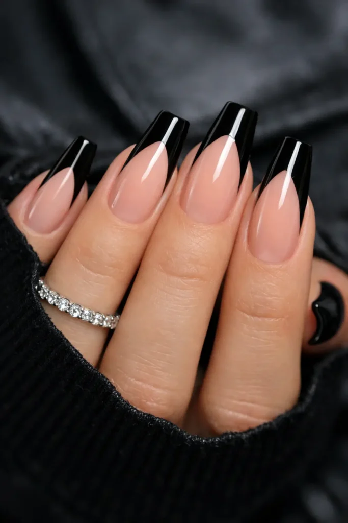 Black french tip nails with bold black tips on nude base on coffin shaped nails