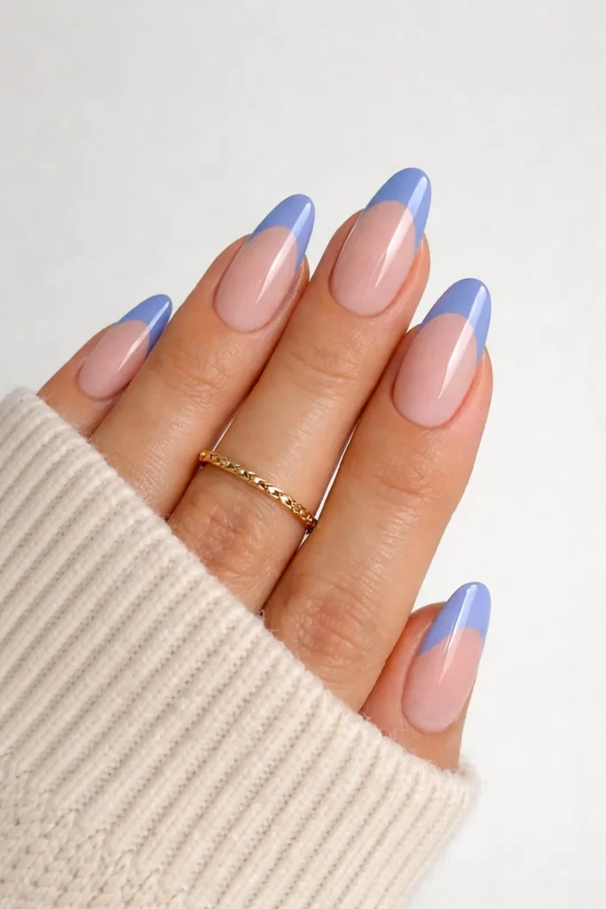 Blue french tip nails with dusty periwinkle blue tips on nude base almond shaped nails