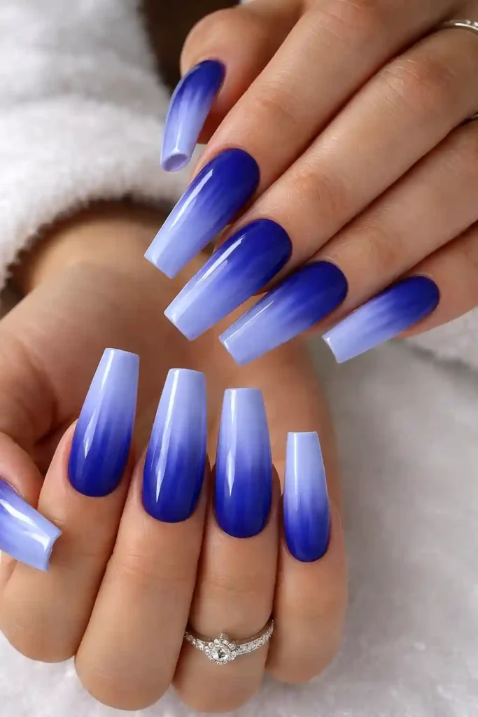 Blue ombre coffin nails fading from deep cobalt at the base to icy periwinkle at the tip