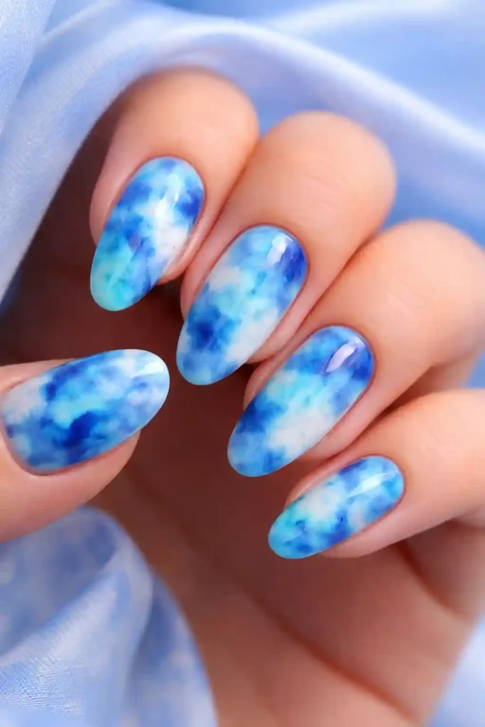 Playful blue tie-dye nail art in sky blue, teal, and indigo
