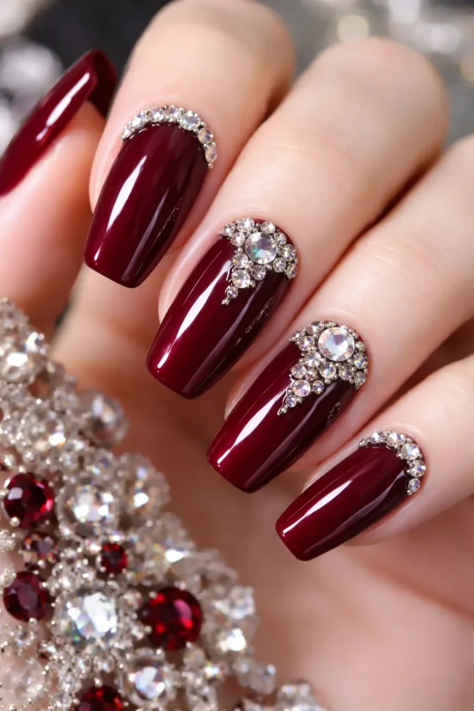 Burgundy nails with rhinestone crystal gemstone accents along cuticle line

