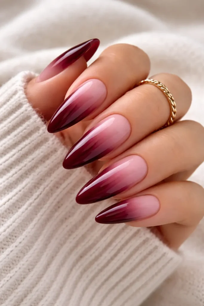 Burgundy ombre nails fading from deep wine to blush nude on almond shape
