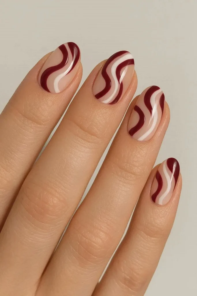 Burgundy swirl nails with abstract hand-painted fluid design on almond shape
