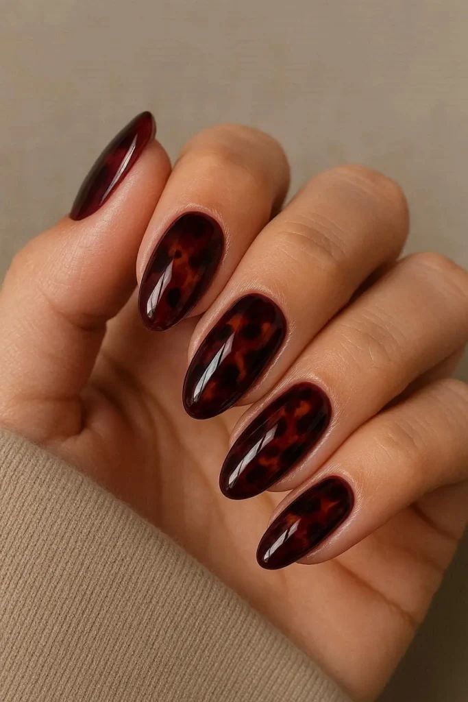  Burgundy tortoiseshell nails with amber and brown tones on almond oval shape
