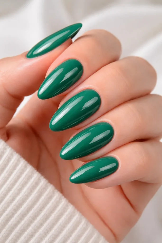 Classic glossy jade green nails with a high-shine top coat on almond shaped fingers