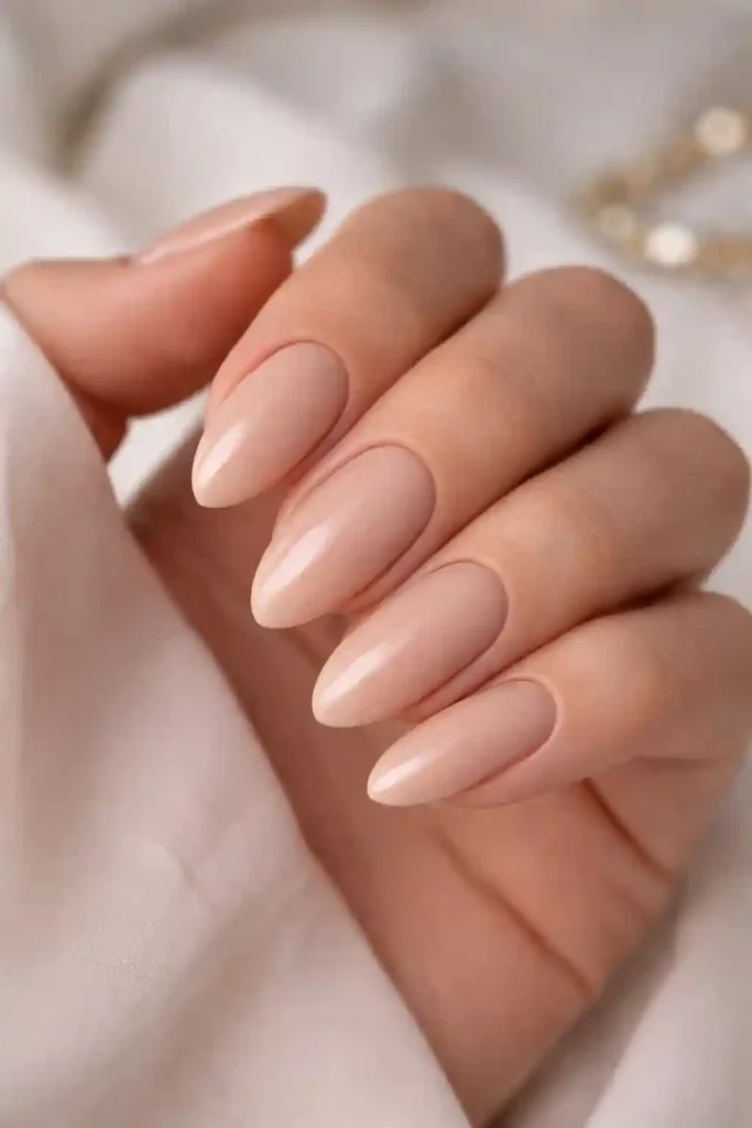 Classic nude almond nails in soft beige on long fingers