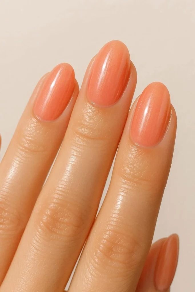 Coral glazed donut nails with a sheer coral base and ultra glossy wet look finish on short almond shaped nails