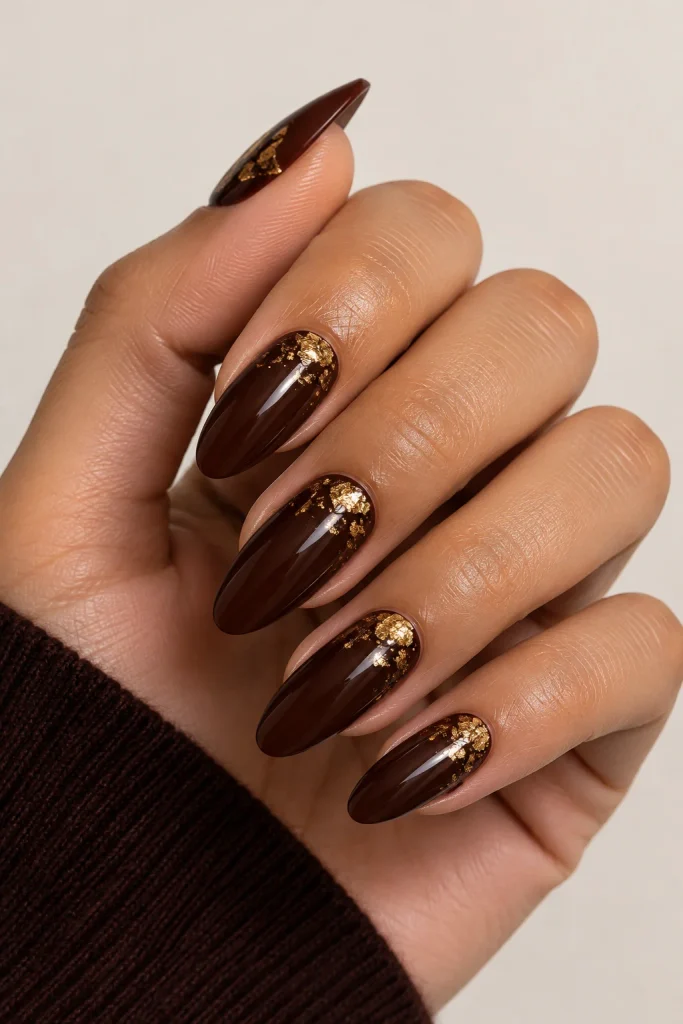 Dark brown nails decorated with delicate gold foil