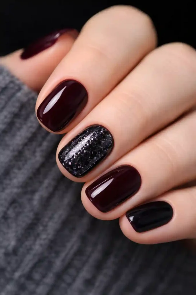 Dark glitter accent nails with one sparkling nail among deep burgundy short nails