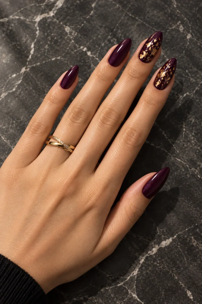 Deep eggplant nails with delicate gold foil accents 
