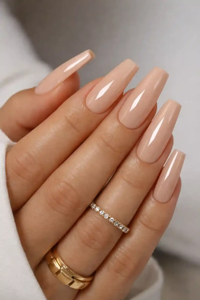Glossy nude coffin nails with a creamy finish on long elegant hands
