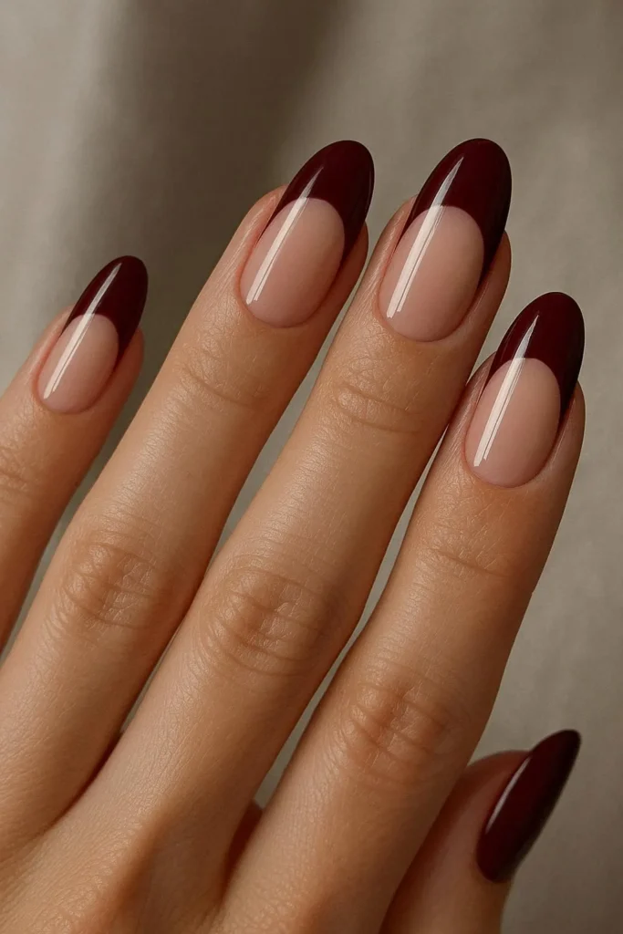 Burgundy half-moon reverse French nails on nude base
