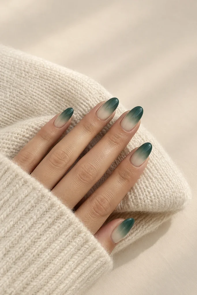Medium oval nails blending deep jade green into warm cream ombré.