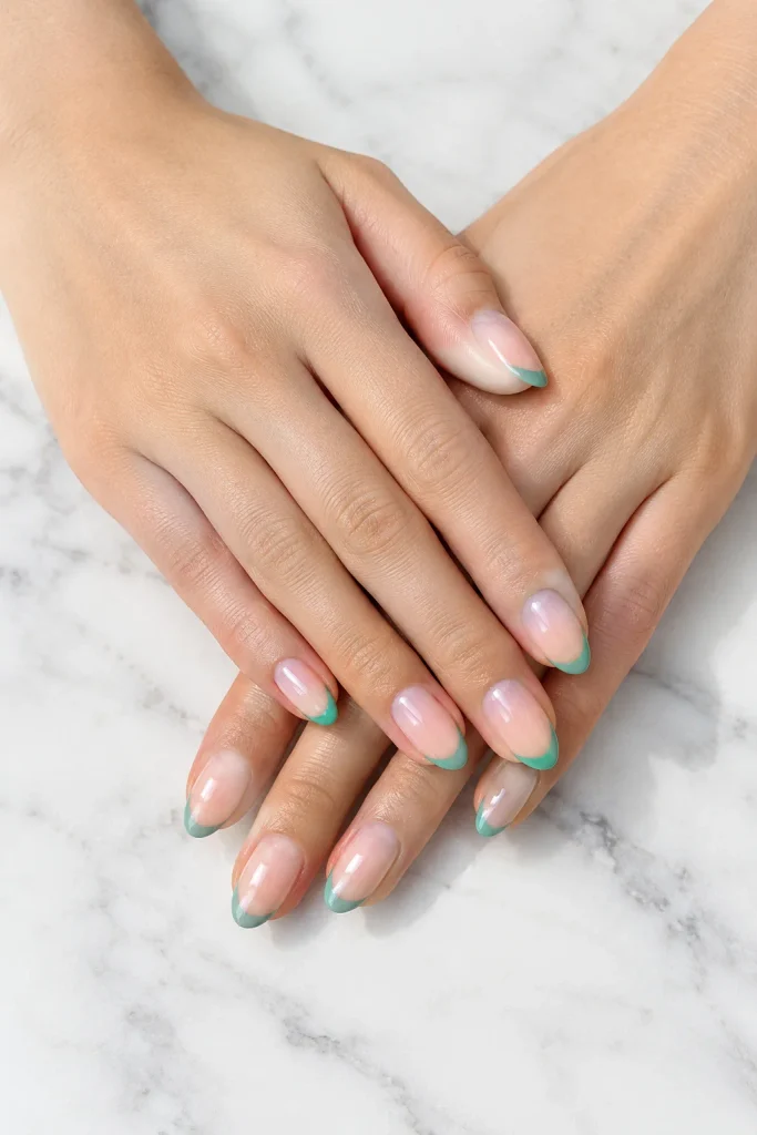 Milky pink almond nails featuring thin jade green French tips.