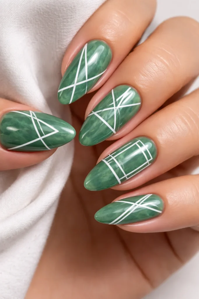 Jade green nails with white geometric line art forming triangles and abstract shapes