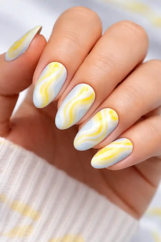lemon yellow and white swirl nails on a pale blue base