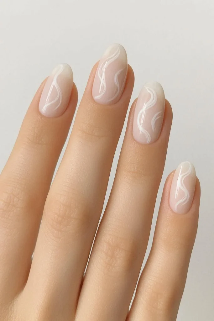 Milky nails with delicate hand painted white swirl nail art over a soft creamy base 