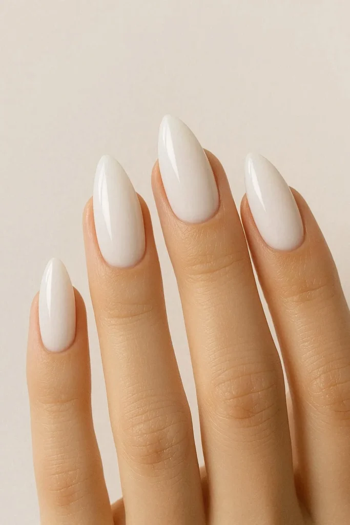 Milky white almond nails with a glossy finish on long tapered almond shaped nails