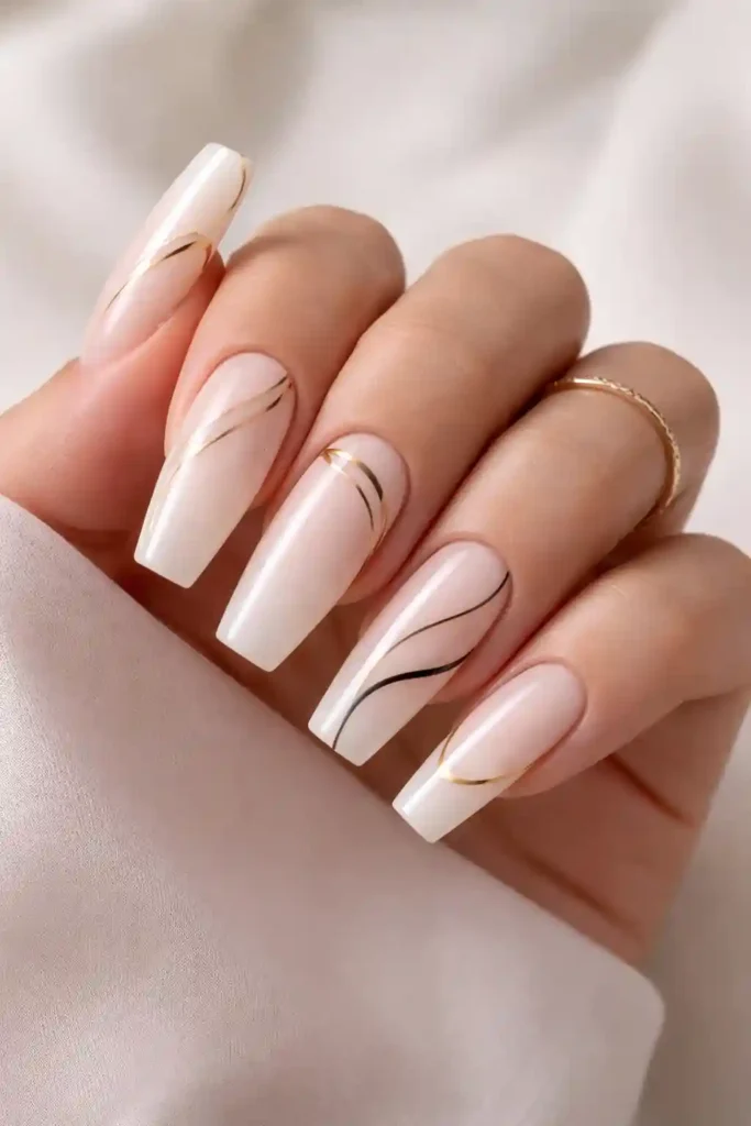 Minimalist line art coffin nails with thin gold lines on a milky white base