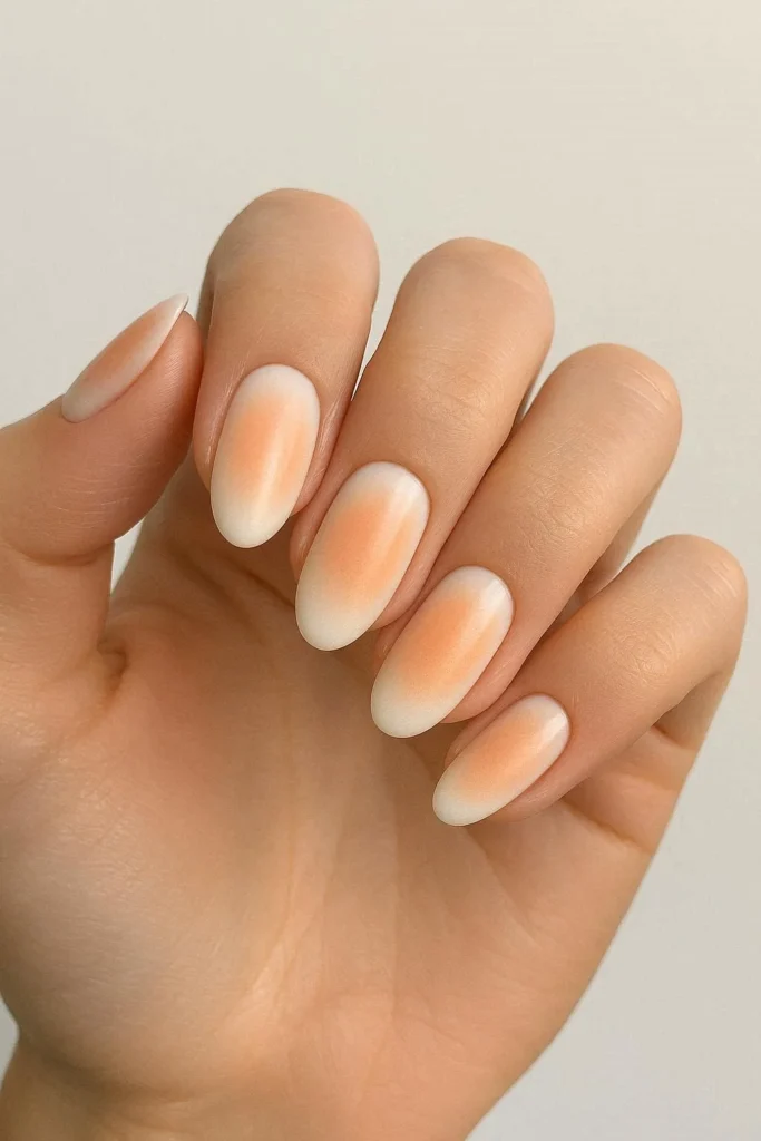 Peach aura nails with a glowing halo of diffused peach color blended over a white base
