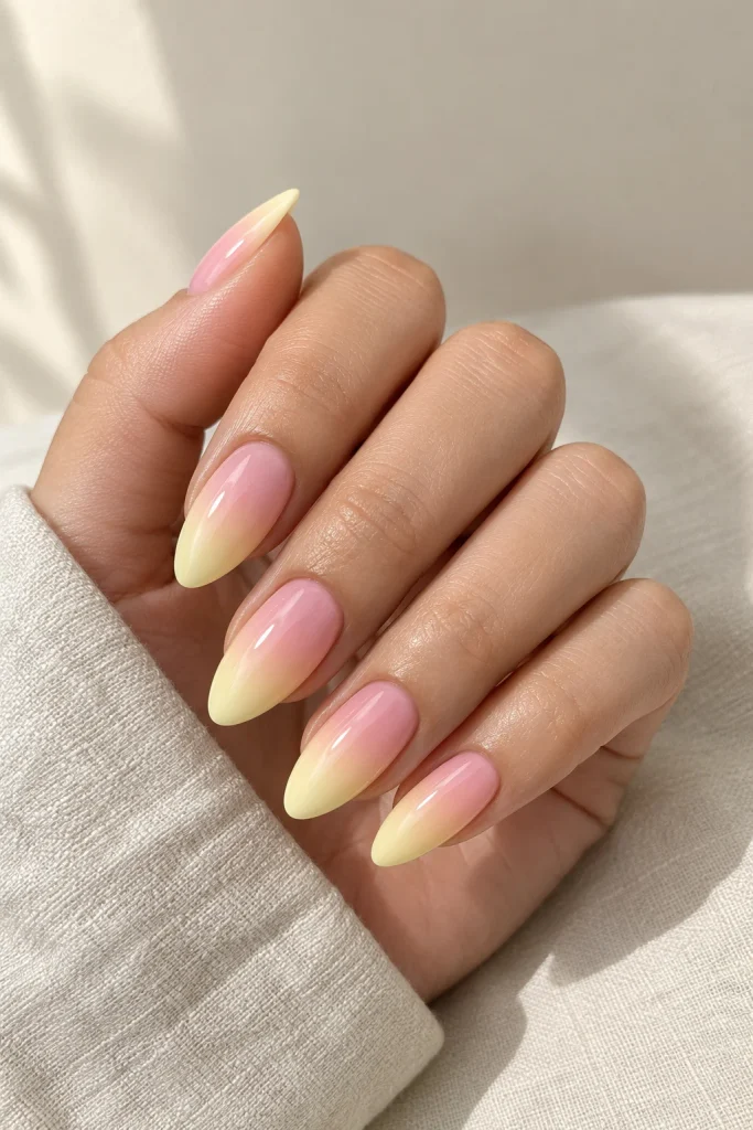 Baby pink and pale lemon yellow gradient almond nails with a glossy finish