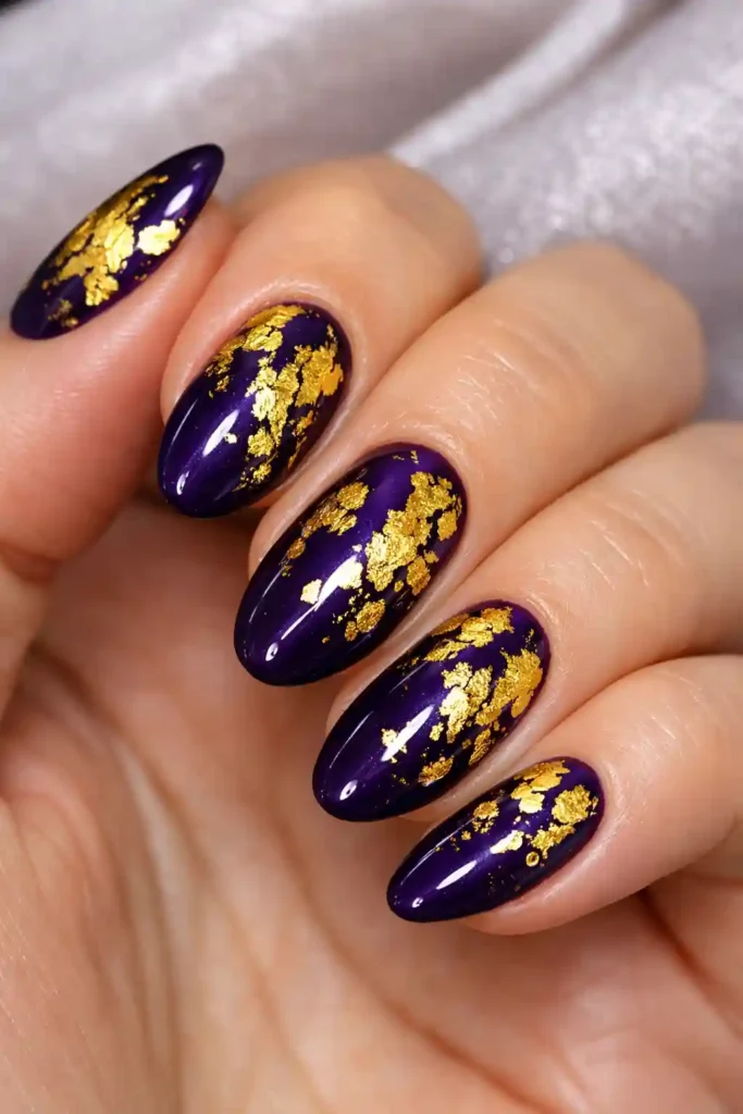 Purple and gold foil nails with deep plum base and shimmering gold foil fragments