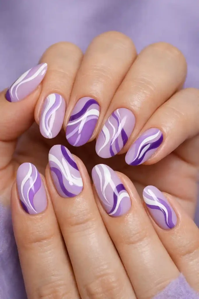 Purple swirl nails with white and lilac swirl nail art on lavender base