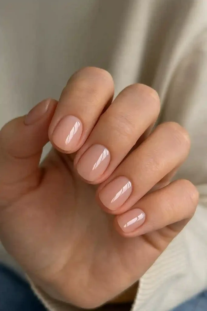 Short rounded gel nails in glossy nude polish for everyday wear
