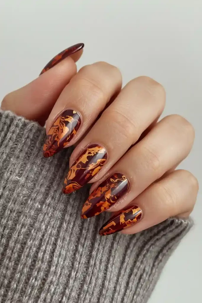 Tortoiseshell almond nails in amber brown and gold marble pattern
