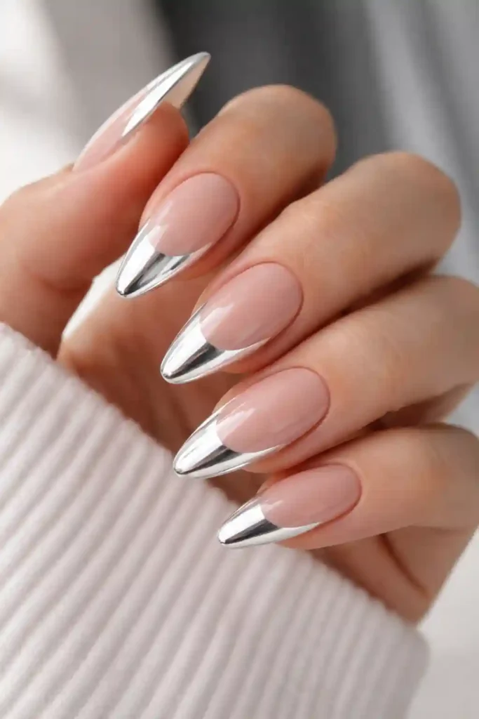White chrome French tip nails with a reflective metallic tip on almond nails