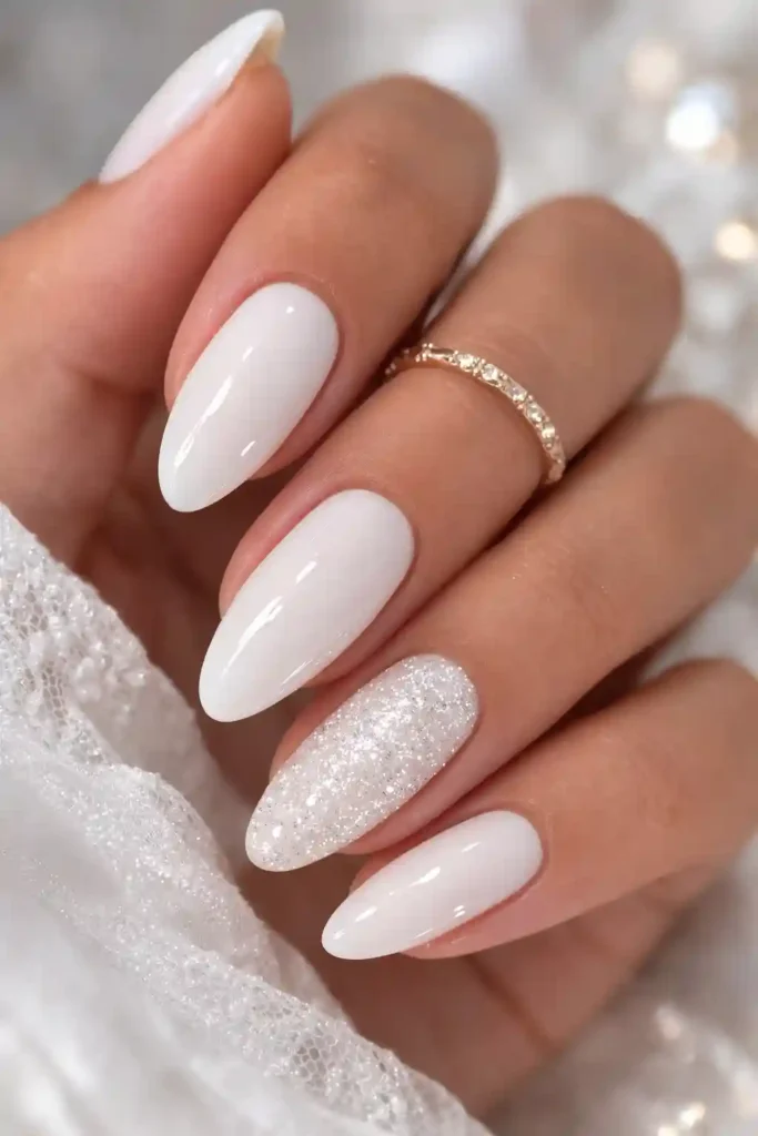 White glitter accent nail on the ring finger paired with four glossy white nails