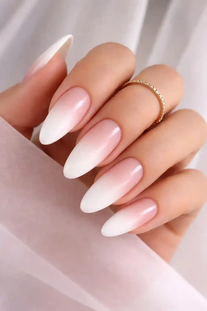 White ombre nails fading from creamy nude at the base to bright white at the tips on almond nails