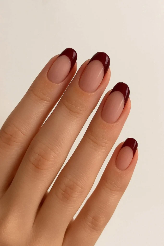Classic French tip nails with a deep moody burgundy twist