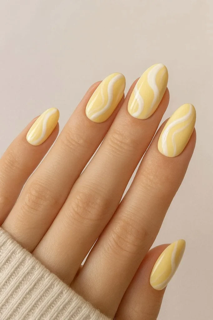 Butter yellow nails with white swirl nail art design 