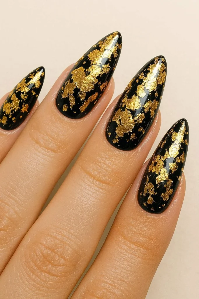 gold foil statement nails with metallic flakes over dark base