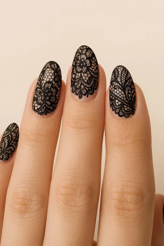 Bold black lace nail art over a neutral nude background 