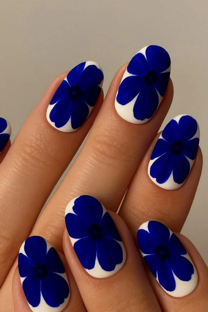  Bold deep blue floral nail design on white base 
