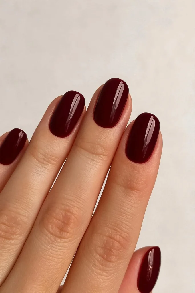 Burgundy glossy holiday nails with gold foil festive detail