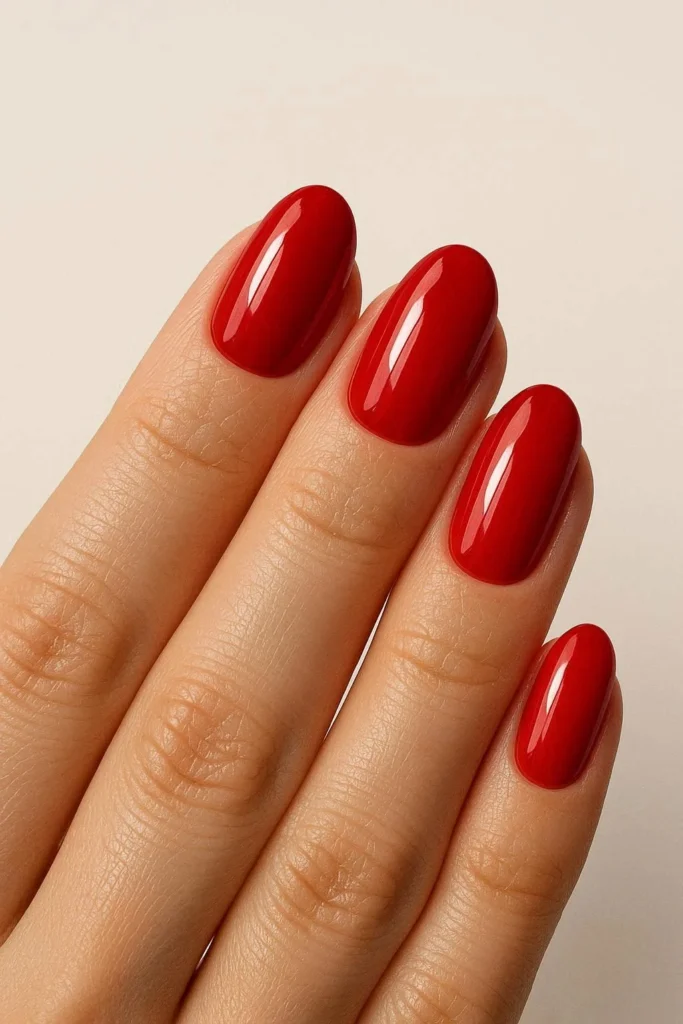 Glossy red oval nails with bold cherry finish on rounded shape