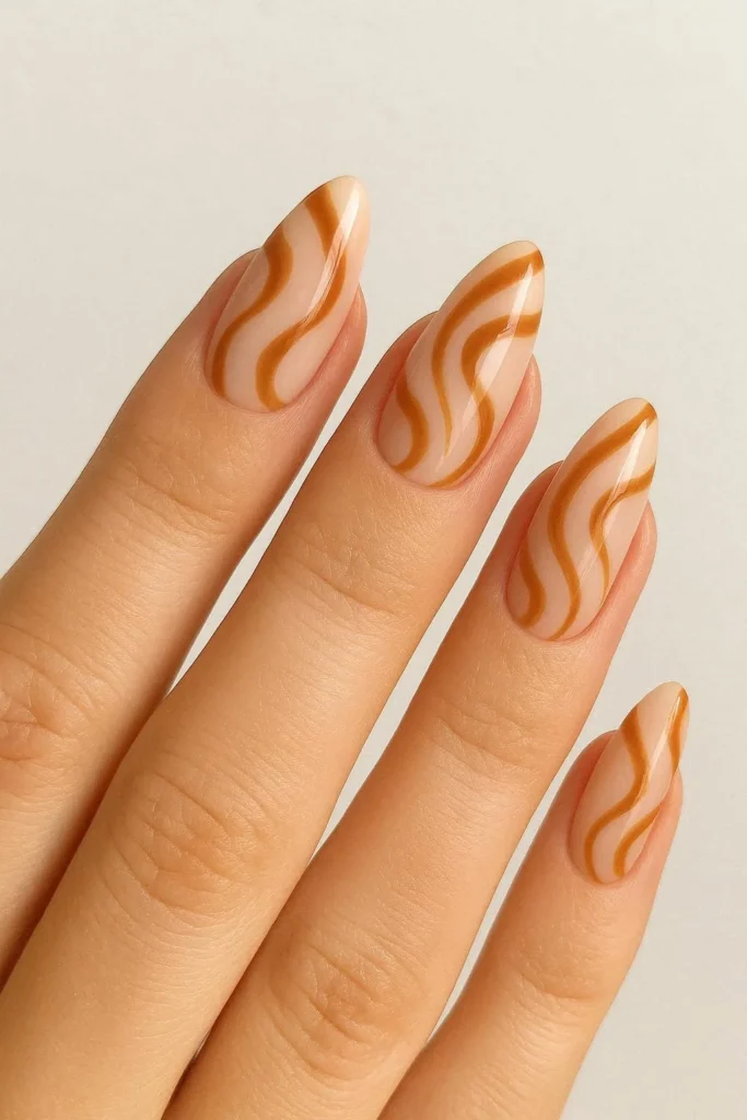 Almond shaped nails with flowing caramel swirl pattern